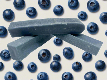 Image of three blue blueberry yak chews on a white background with multiple blueberries 