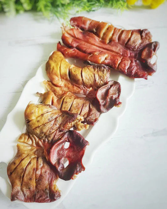 Image of three pig snouts on a white plate sitting on a white surface 