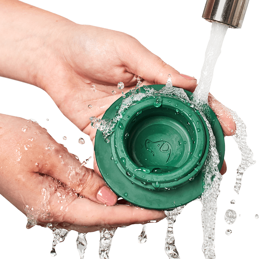 Image of hand washing a green pupsicle ball under running water