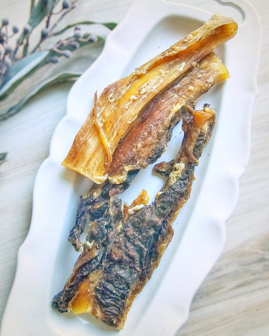 Image of two pieces of beef backstrap on a white plate that is on a light wood surface