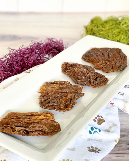 Image of four pieces of beef brain on a white plate with a cloth that has paw prints and bones 