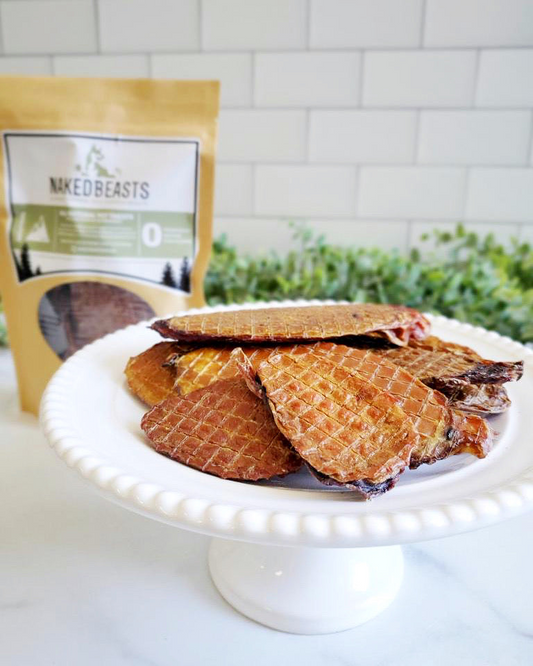 Image of multiple bull fries on a white plate with a product bag and greenery in the background in front of a white tile backsplash 