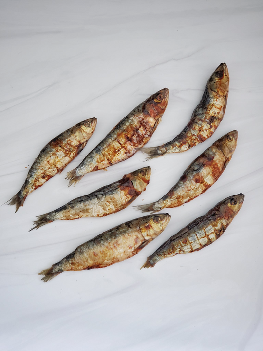 Image of seven sardines laid out on a white marble surface 