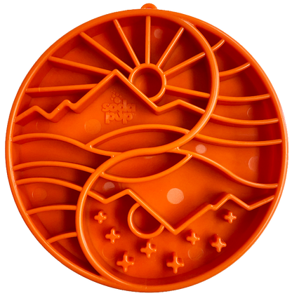 orange slow feeder bowl with a mountain, sun and tree pattern.