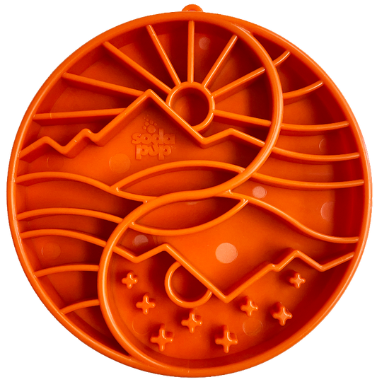 orange slow feeder bowl with a mountain, sun and tree pattern.